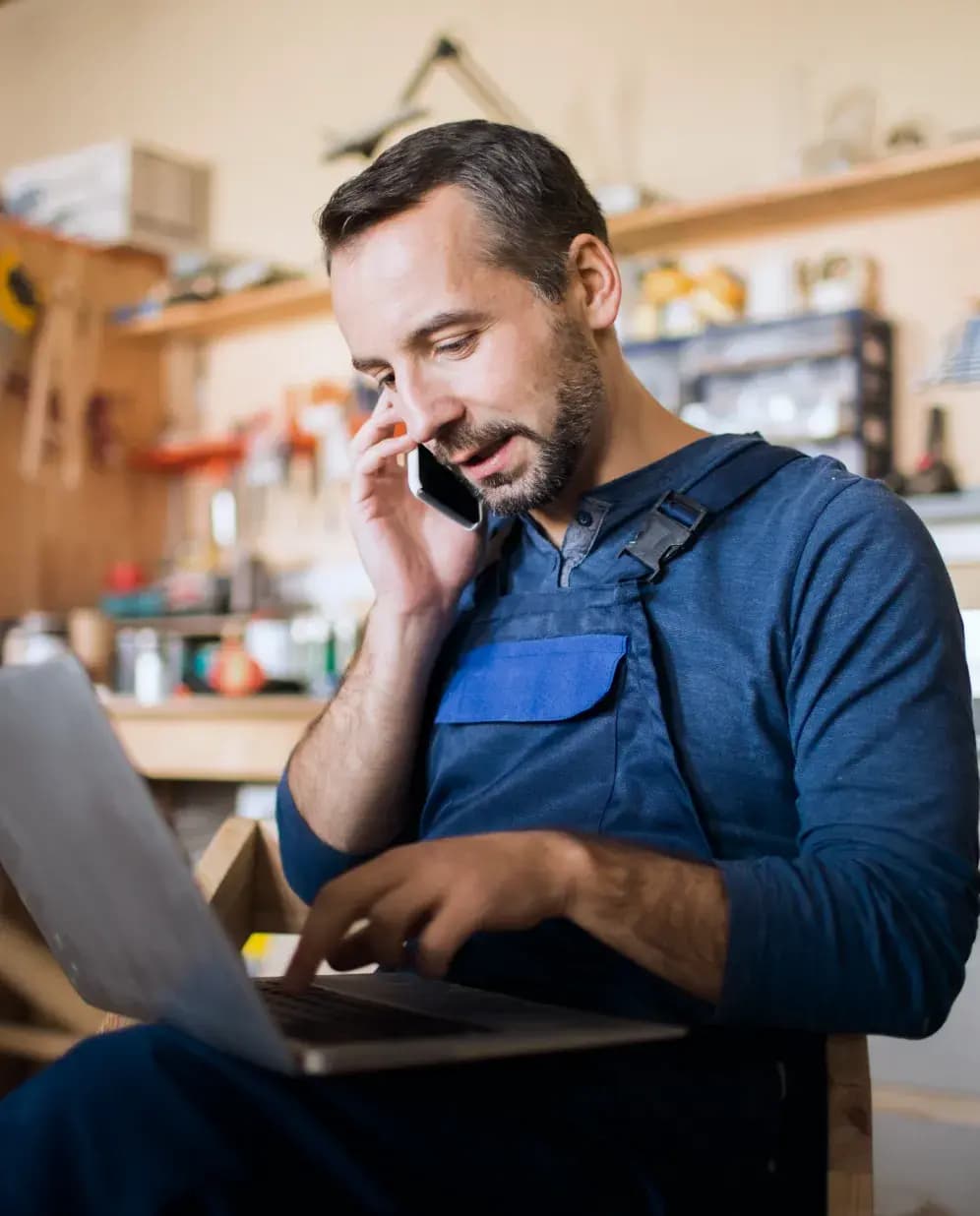 Mann telefoniert und blickt auf Laptop